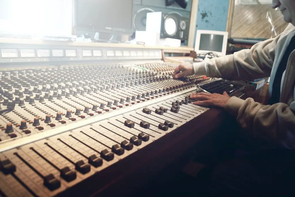 Image of a person adjusting the controllers of an audio mixer. Source: pexels