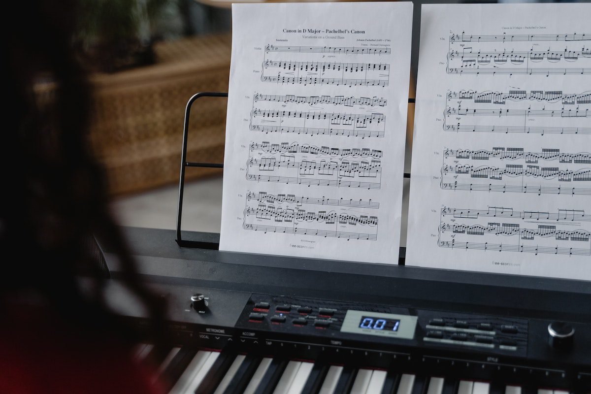 Image of a person reading a music sheet in a piano stand. Source: pexels