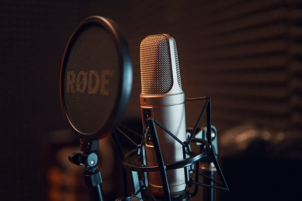 Image of a silver microphone with a filter on a black microphone stand. Source: pexels