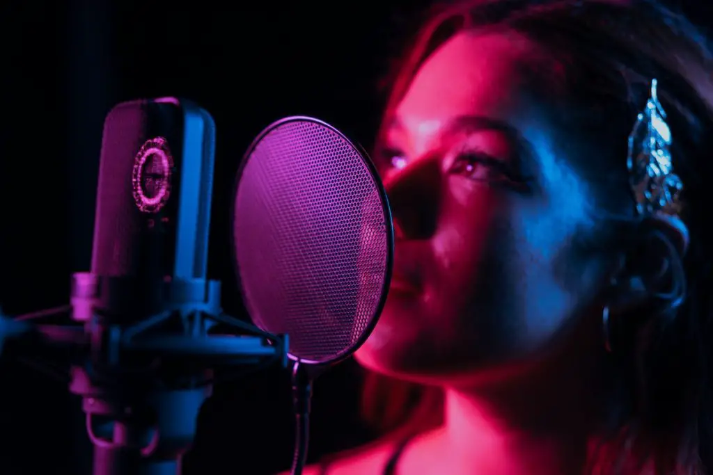 Image of a woman singing in front of a mic with a pop filter pexels