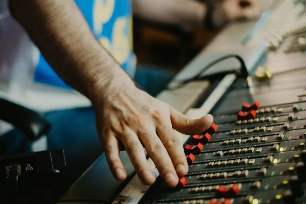 Image of an audio engineer adjusting a mixer. Source: pexels