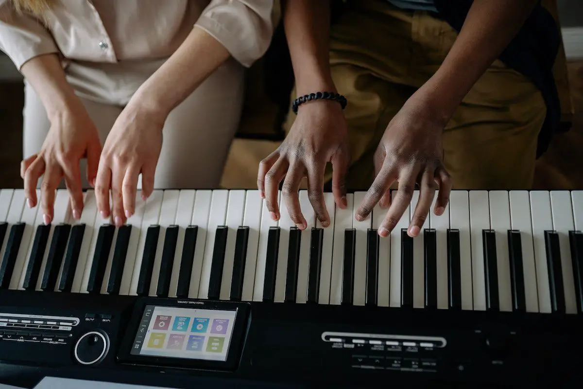 Image of two people playing an electronic organ. Source: pexels