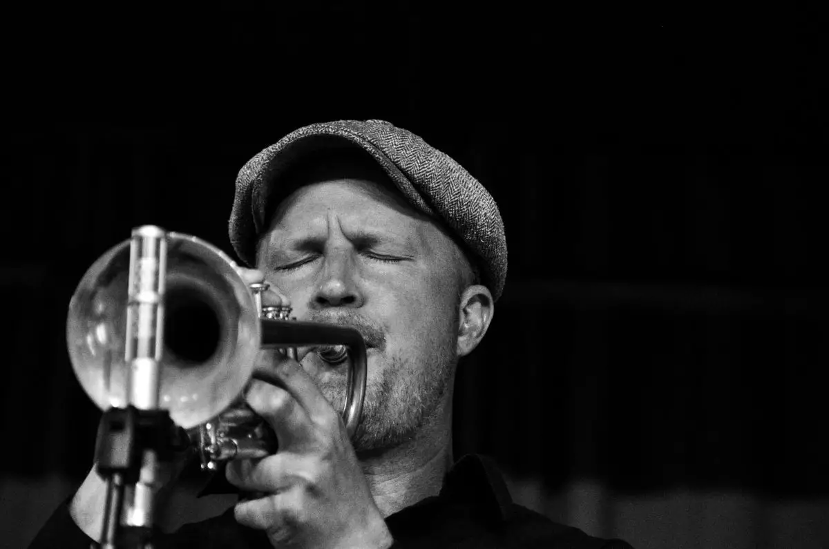 Image of a man playing jazz music using his trumpet.