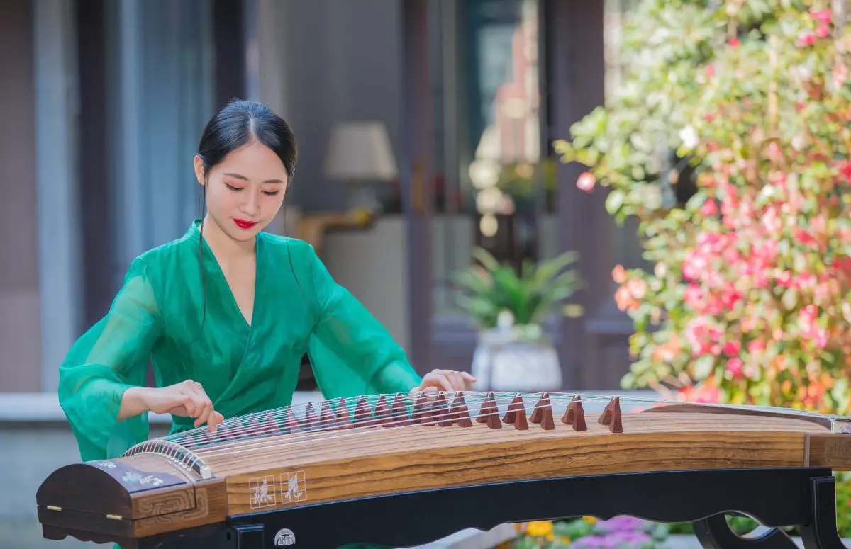 Image of a woman in a green dress playing the zither.