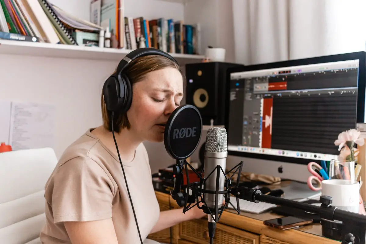 Image of a woman singing on a microphone in a home studio.