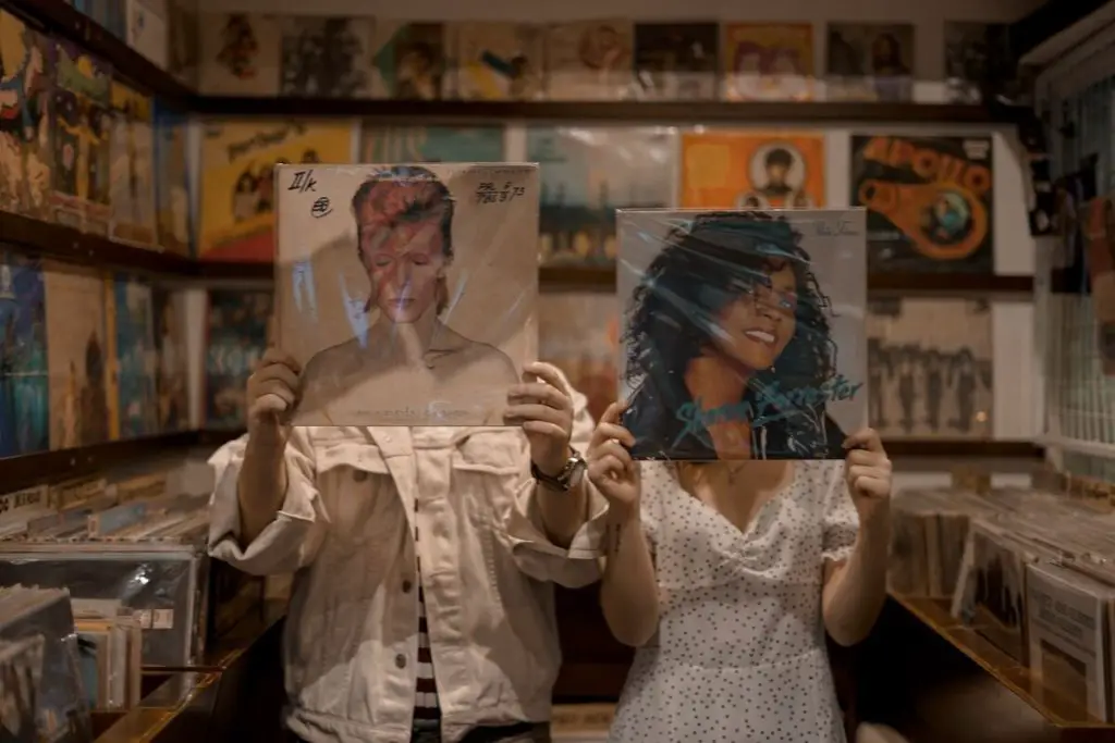 Image of two persons holding up a david bowie and sharon forrester vinyl record. Source: unsplash