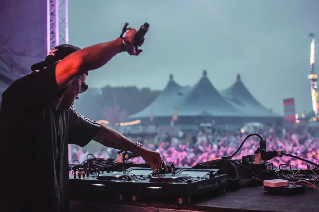 A dj mixing music in a festival. Source: unsplash