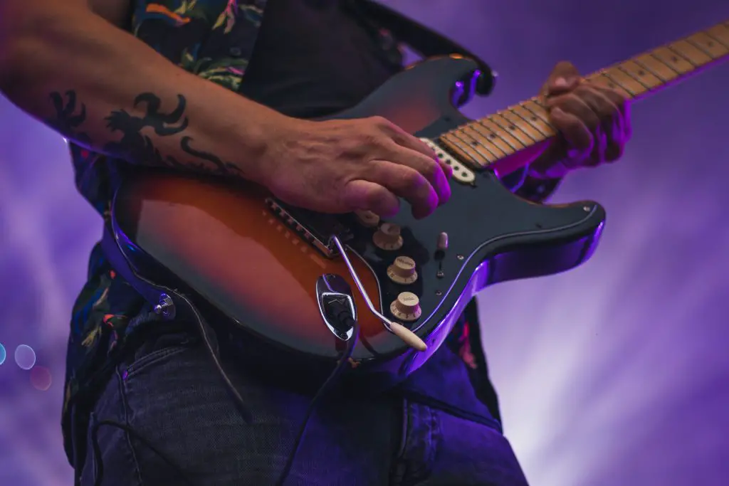 Closeup of an electric guitar being played by a guitarist. Source: unsplash