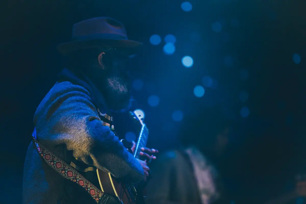 Image of a blues musician performing with a guitar. Source: unsplash
