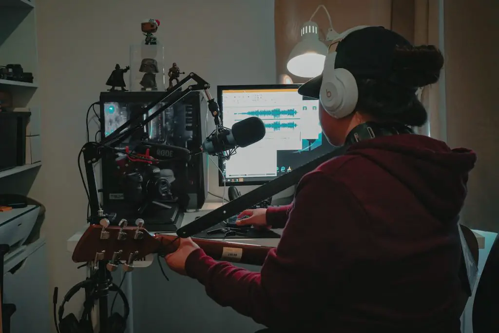 Image of a guitarist with wireless headphones while recording in a studio. Source: Pexels