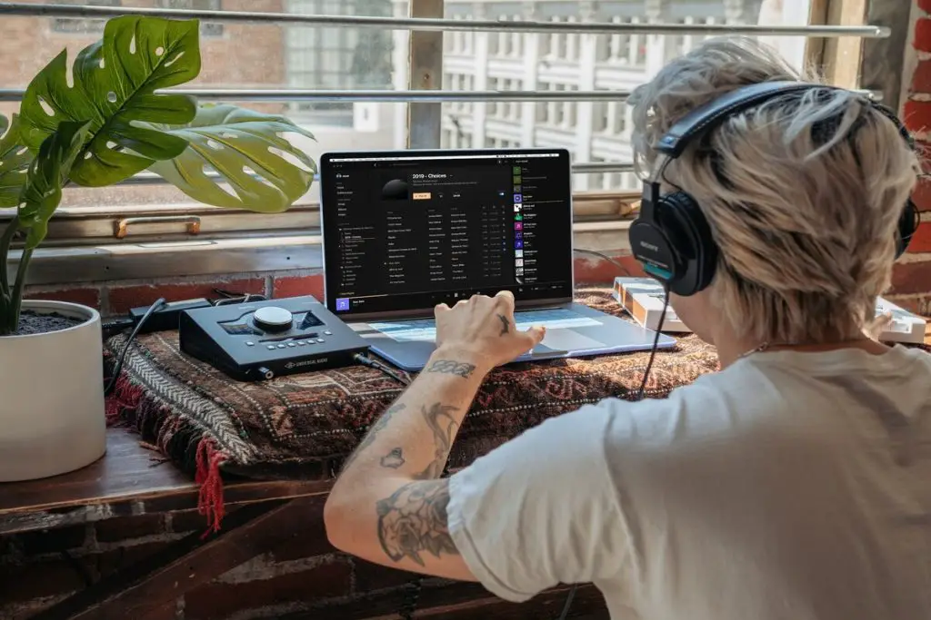 Image of a man listening to music through headphones while in front of a laptop. Source: unsplash