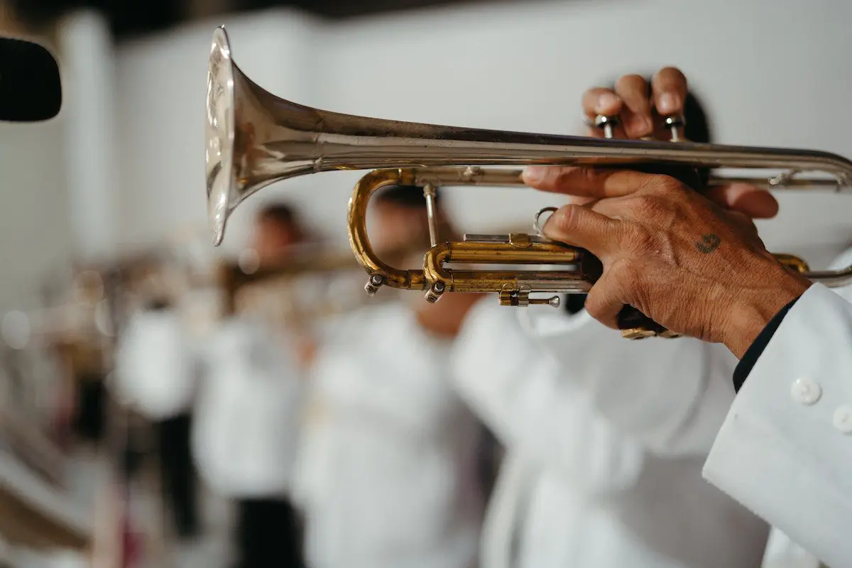 Image of a man playing a trumpet in a band. Source: pexels