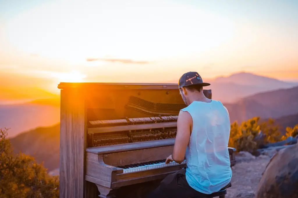 Image of man playing piano outdoors. Source: unsplash