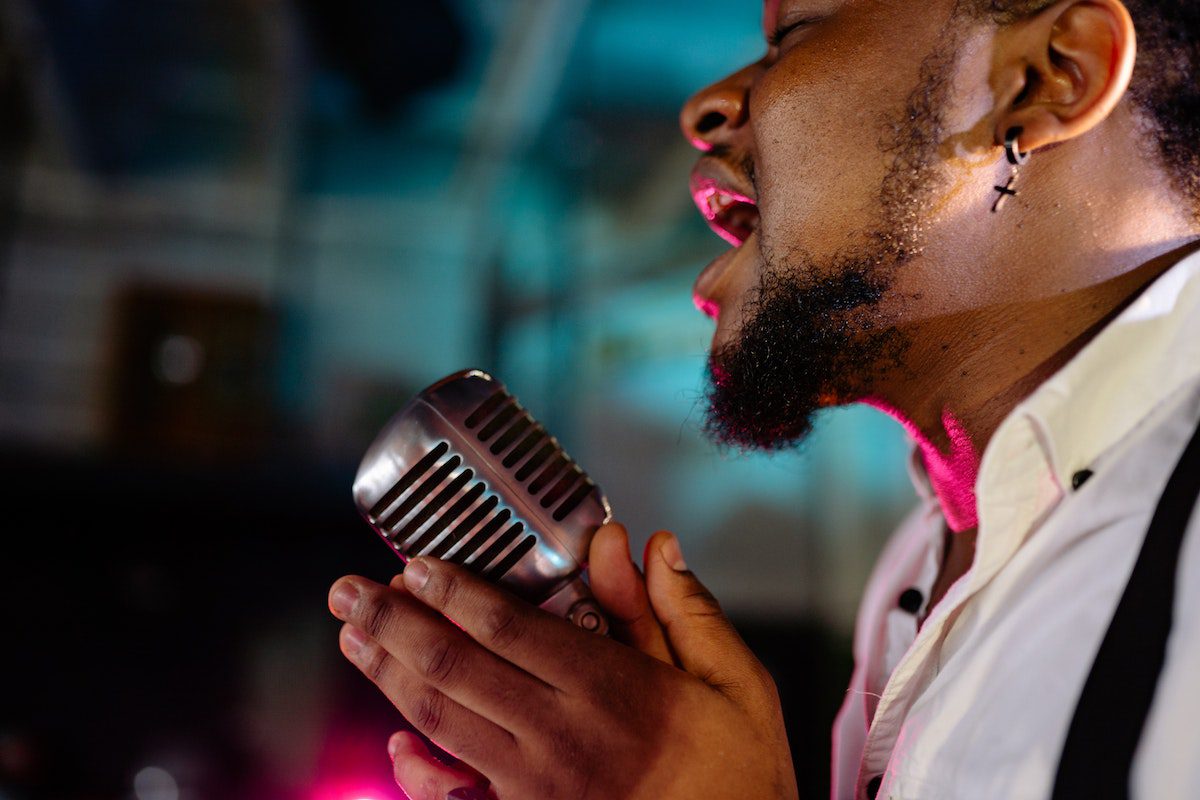 Image of a man singing on a microphone. Unsplash