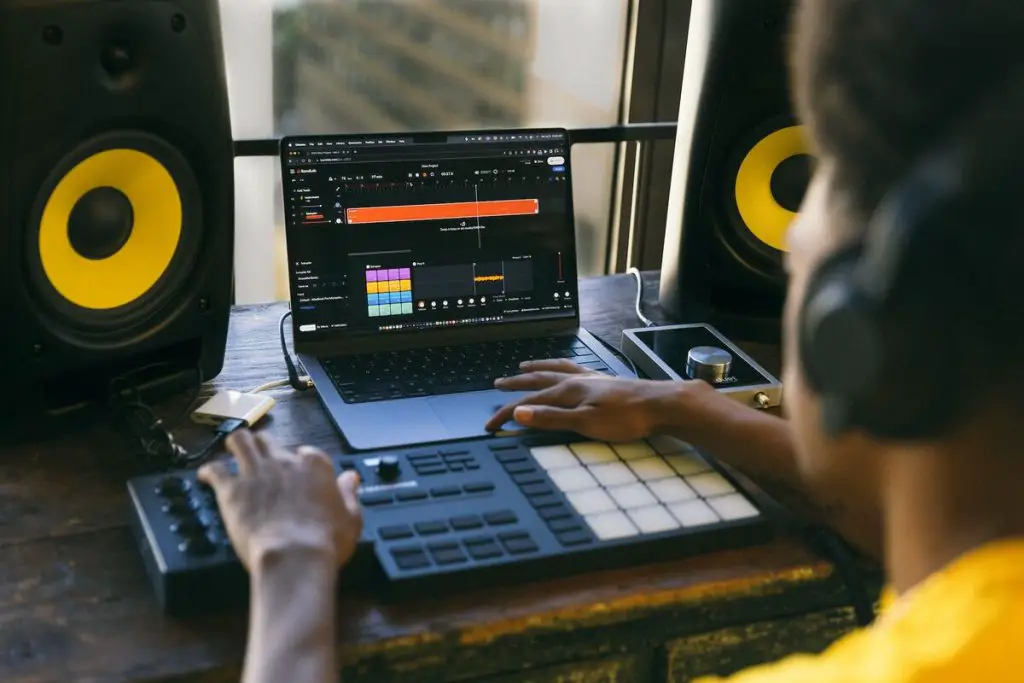Image of a man using a midi controller in a home studio. Source: unsplash