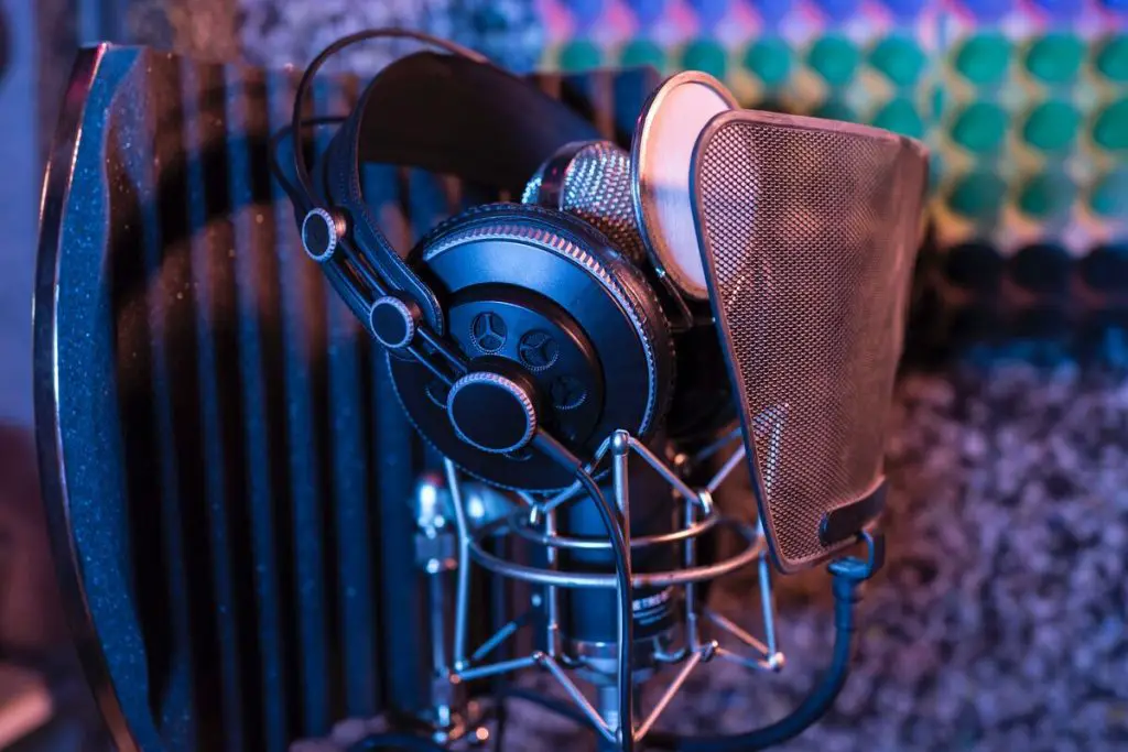 Image of a microphone and headphones inside a recording studio with soundproof foam panels. Source: unsplash