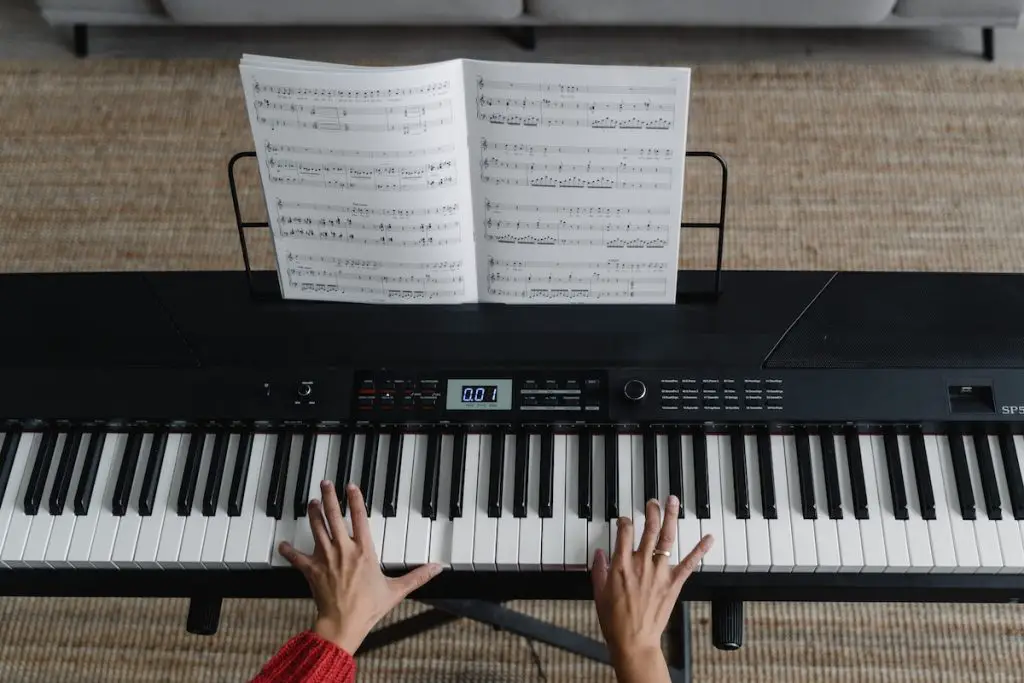 Image of a musician playing the keyboard with a music sheet. Source: pexels