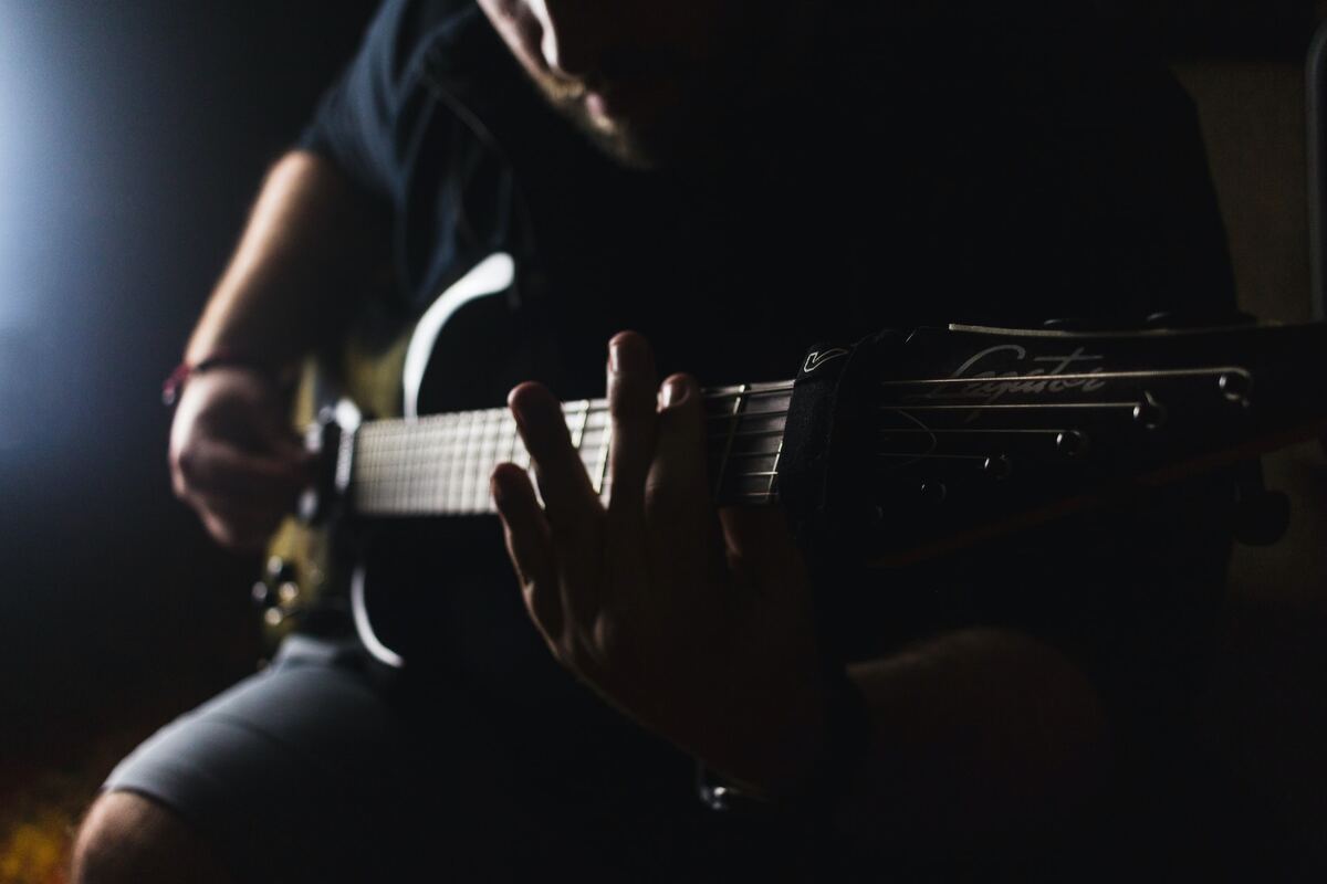 Image of a musician practicing a guitar riff on an electric guitas unsplash