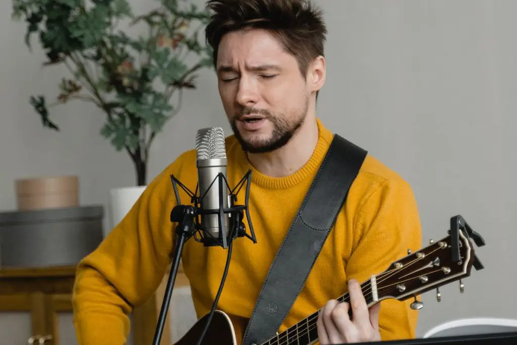 Image of a musician singing a ballad while playing a guitar pexels