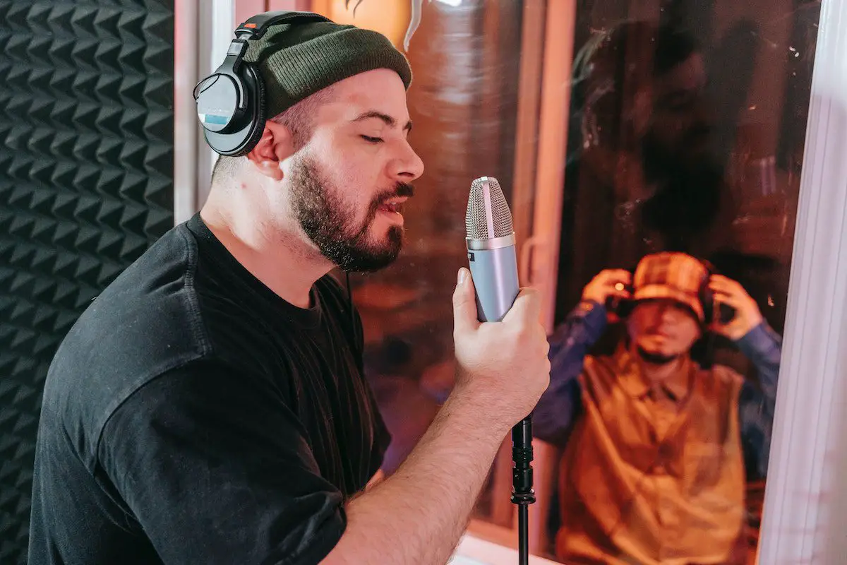 Image of a singer recording in a vocal booth. Source: pexels
