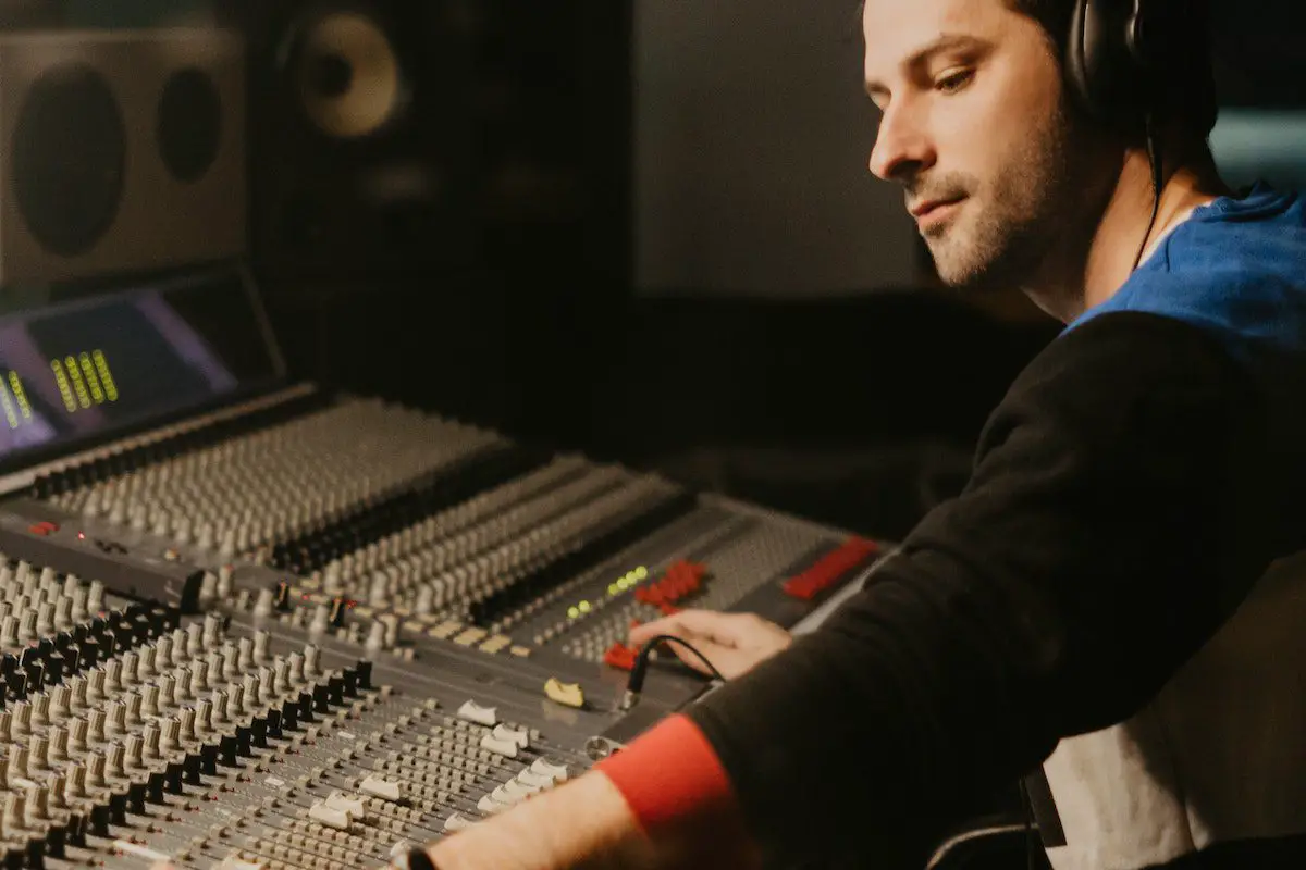 Image of a sound engineer adjusting audio mixers in a studio. Source: pexels