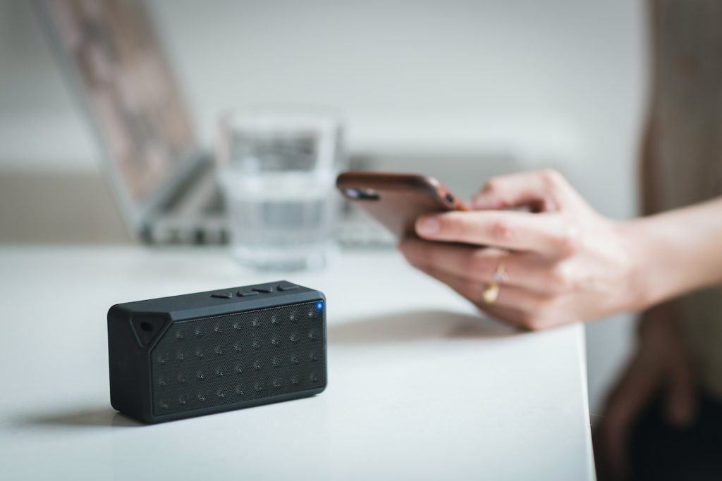 Image of a woman connecting her mobile phone to a bluetooth speaker. Source: unsplash