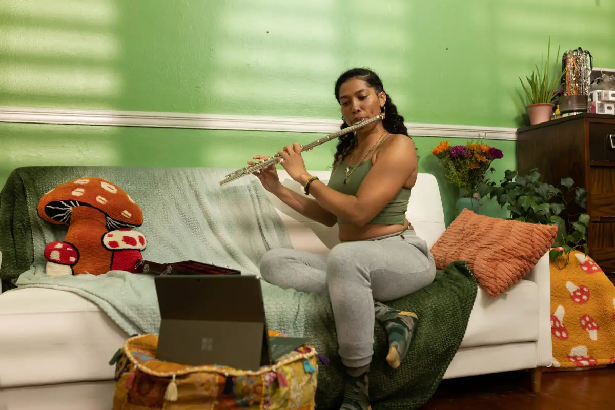 Image of a girl playing the flute in a living room.