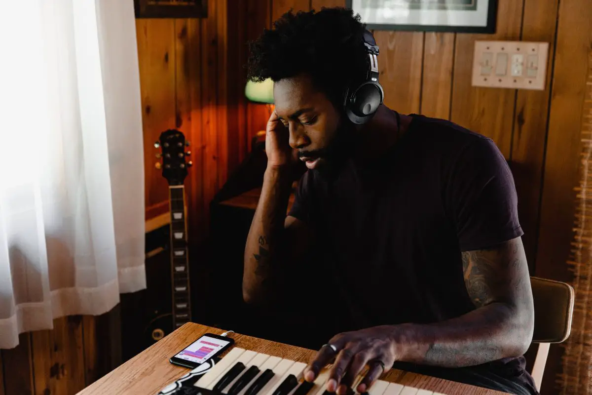 A man wearing headphones and playing a keyboard. Source: unsplash