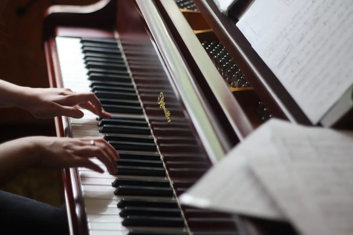Closeup of a piano with a pianist playing. Source: unsplash