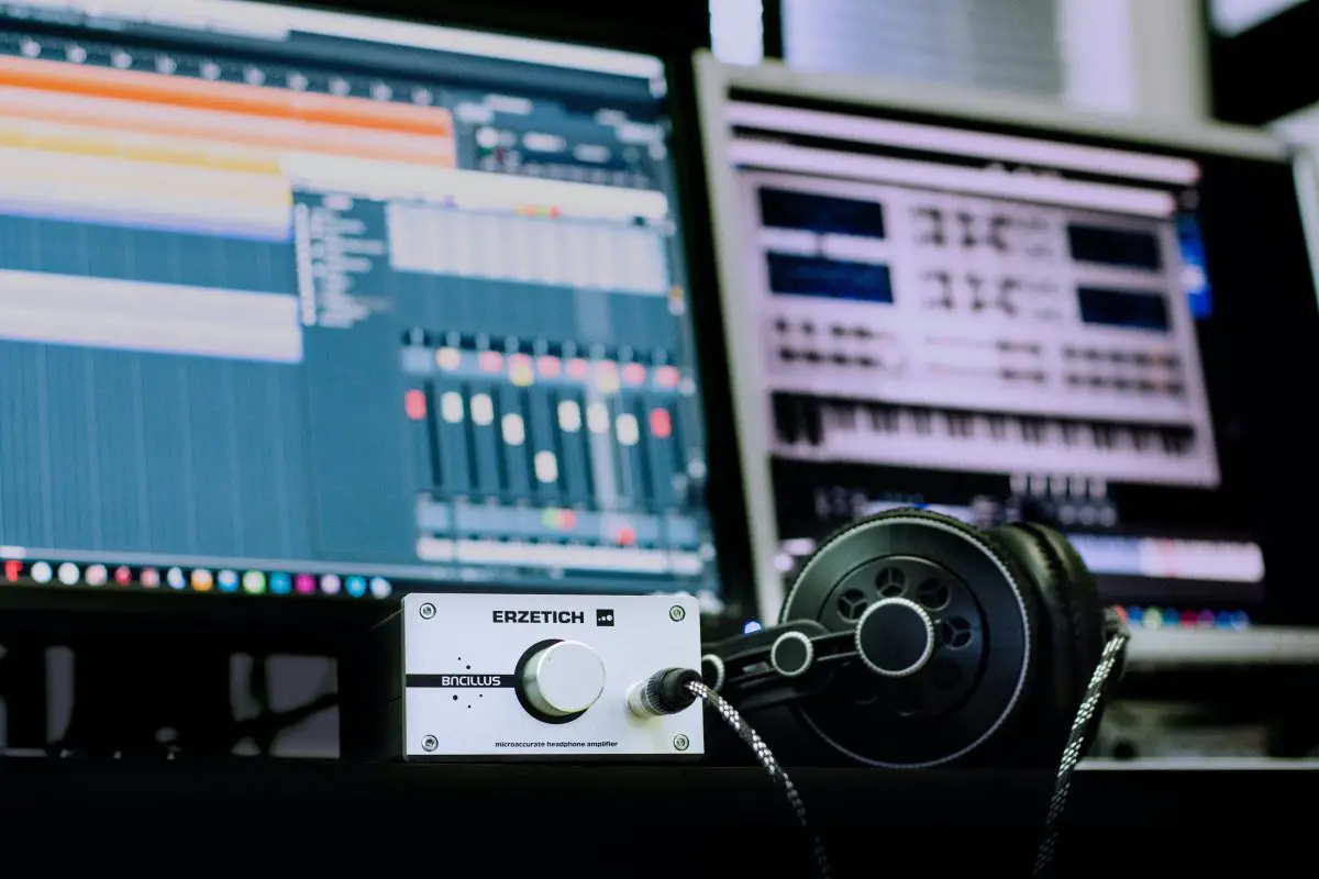 Headphone in front of a computer with other audio equipment. Source: pexels