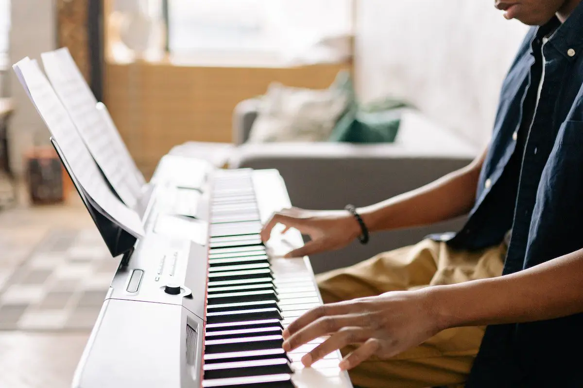 Image of a man playing a keyboard piano. Source: pexels