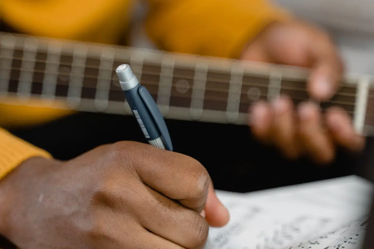 Image of a musician writing on sheet music. Source: pexels