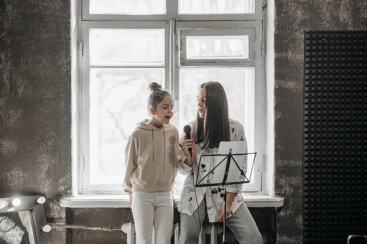 Image of a student with a vocal coach. Source: pexels