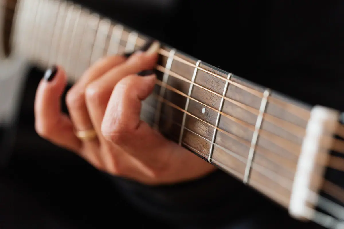 Image of a woman playing a guitar chord. Source: pexels