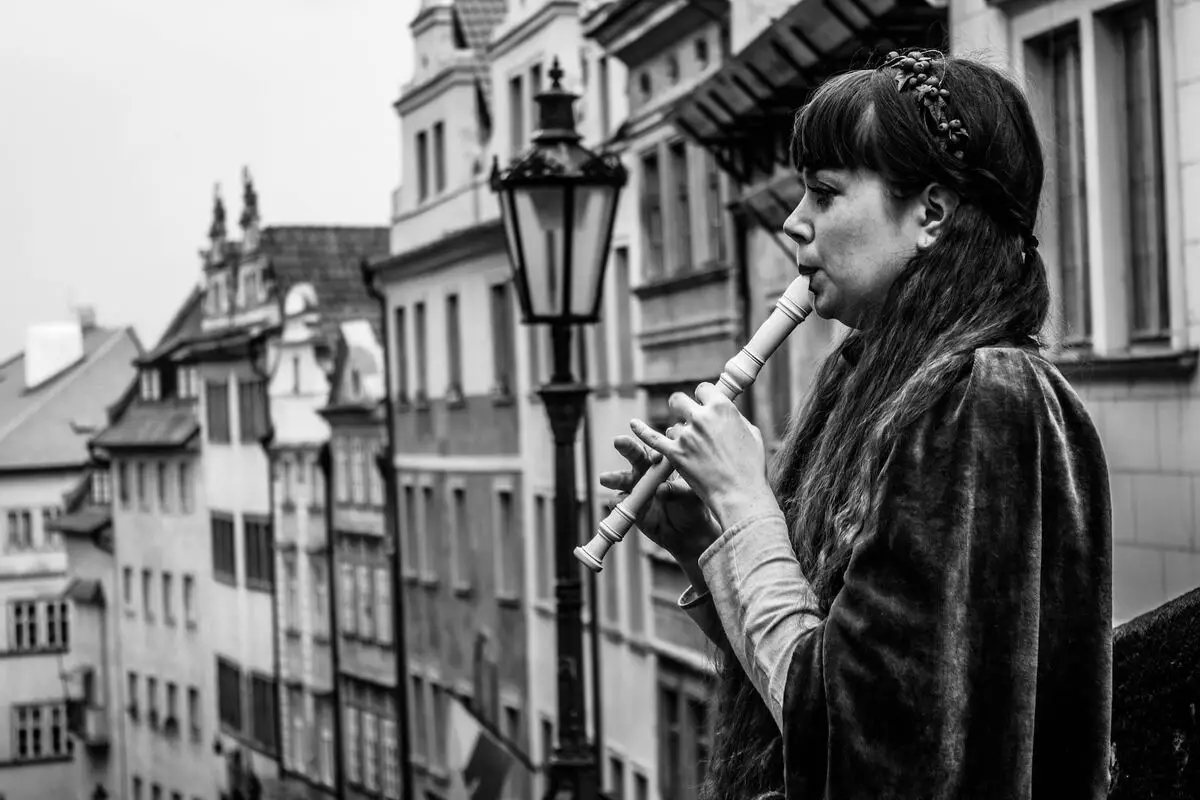 Image of a woman playing the recorder instrument in a balcony. Source: unsplash