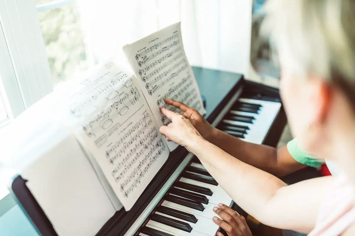 Image of pianists pointing at a note on a sheet music pexels