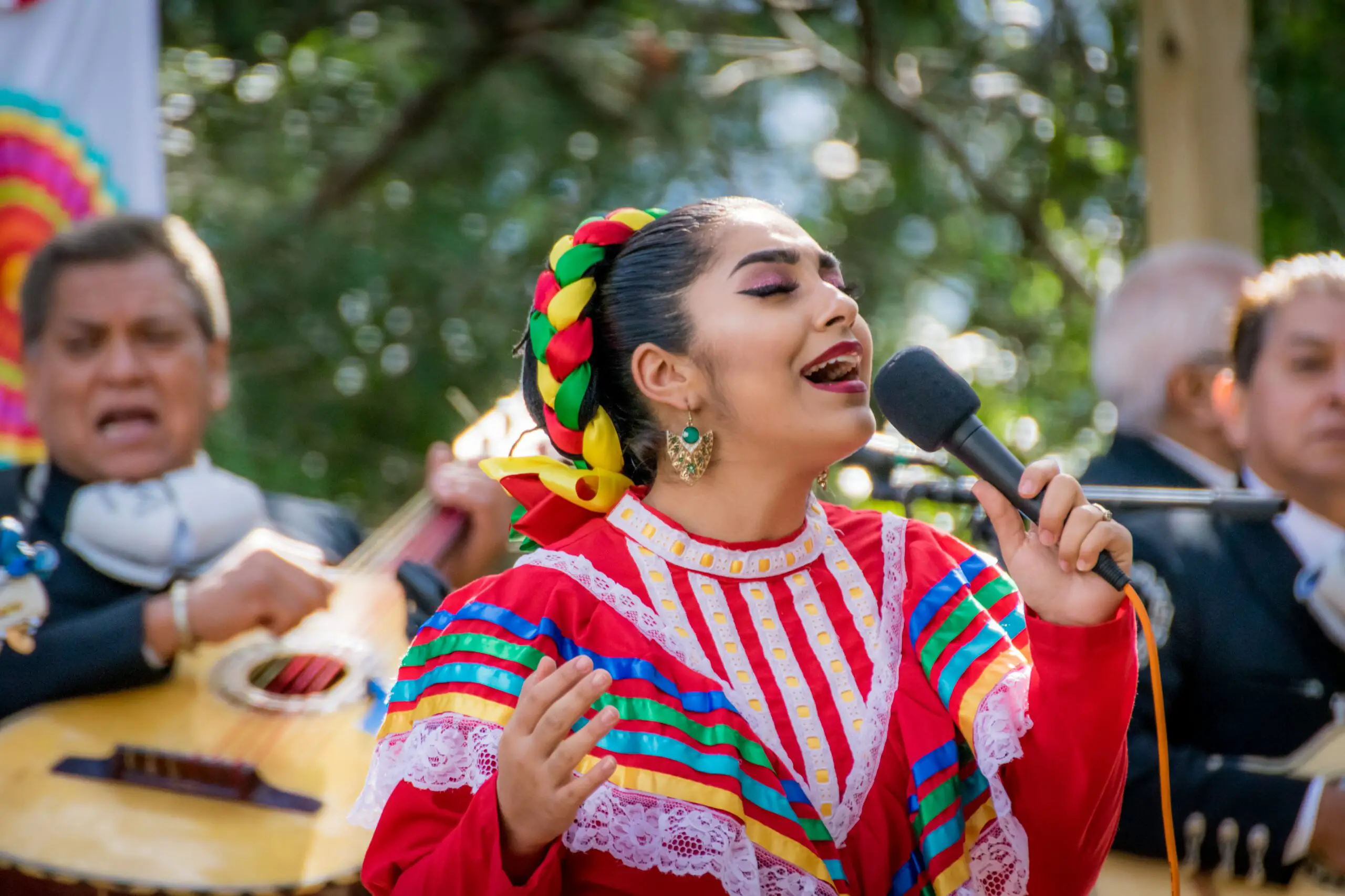Image of a female performer singing while wearing colorful dress.