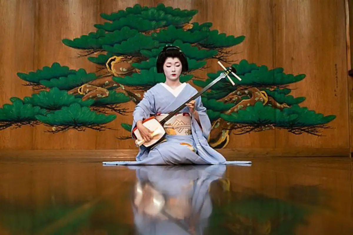 Image of a geisha while playing a shamisen.