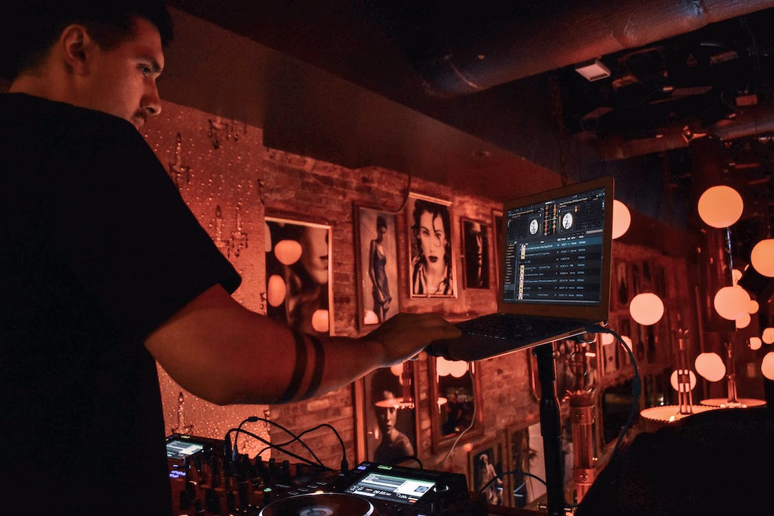 Image of a man editing audio using a laptop and a mixer.