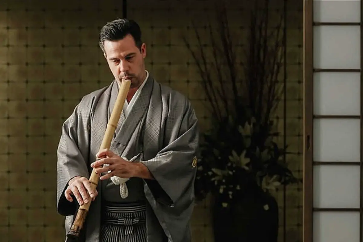 Image of a man playing a shakuhachi flute.