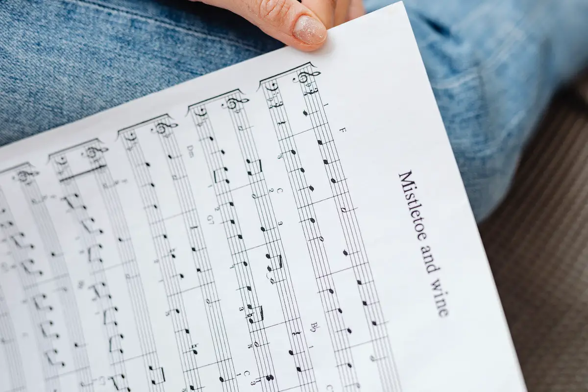 Image of a person holding a sheet music. Source: Pexels