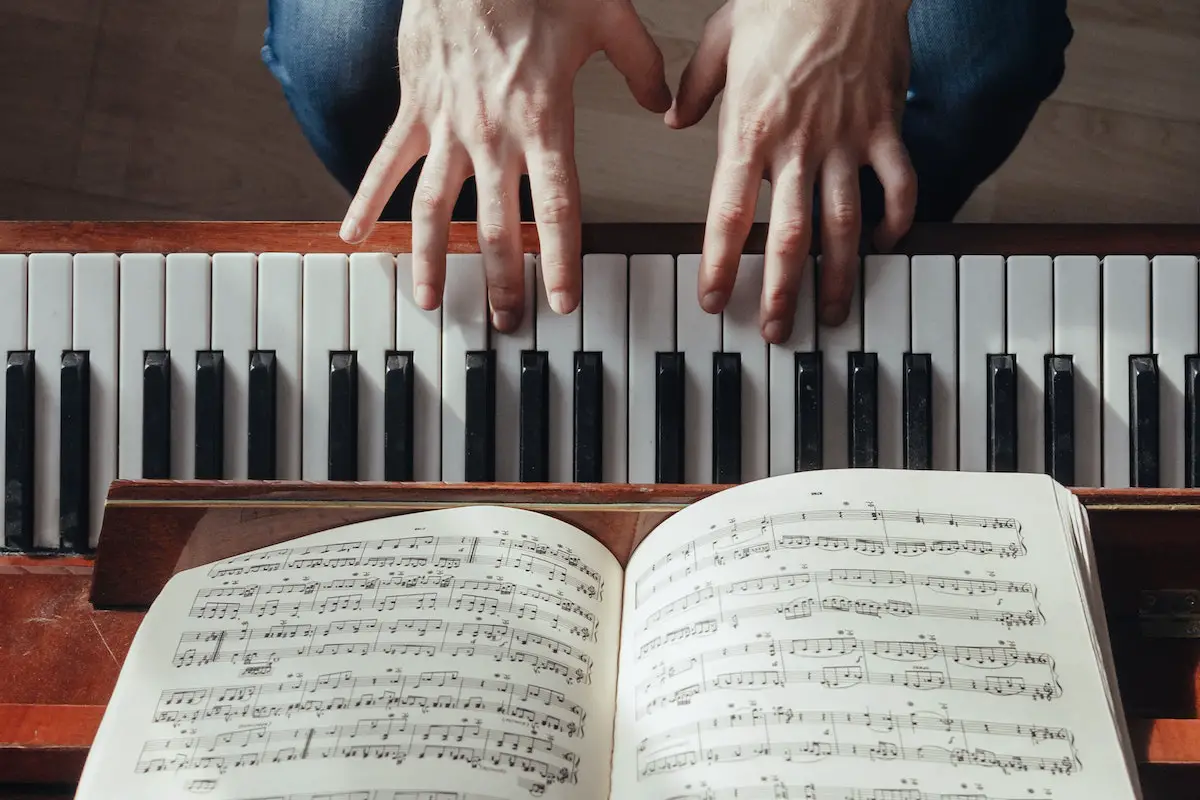 Image of a pianist playing the piano with music sheet on a stand. Source: pexels